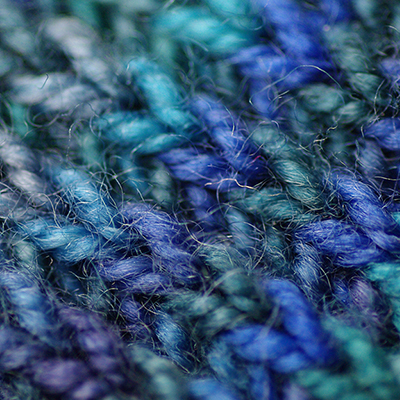 square image showing blue-tonal knitting stitches up close